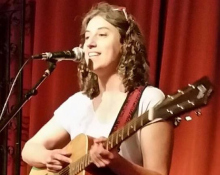 Heather playing a guitar and singing